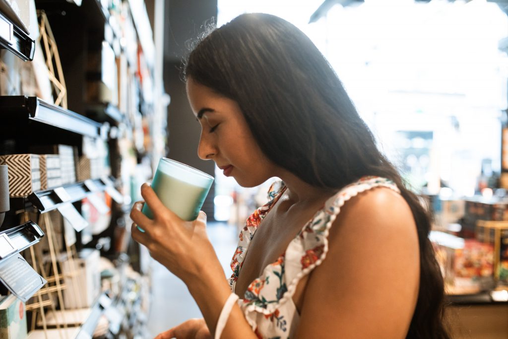 woman sniffing a luxury scented candles aisle